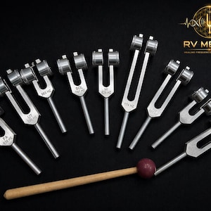 May include: A set of silver tuning forks with frequency markings such as "FA 839 HZ" and "UT 396 HZ", displayed on a black background. A wooden mallet with a maroon head is also present. The logo "RV MEDICS" is visible.