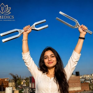 May include: Two silver-colored metal tuning forks with a U-shaped design and a triangular decorative element at the base of the prongs. The tuning forks feature a smooth, reflective surface and a handle with a series of small circular indentations.