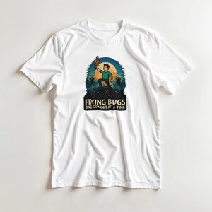 May include: White t-shirt featuring a colorful graphic. The design depicts a person holding a torch, standing atop a pile, with the text "FIXING BUGS ONE COMMIT AT A TIME". The graphic is set against a blue and orange background.