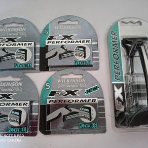 May include: An assortment of Wilkinson Sword FX Performer razor blades and a razor. The packaging is primarily gray and teal, with the brand name and product details clearly displayed. The razor handle is black and white.