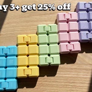 Può includere: Una collezione di colorati fidget toys nei toni del blu, giallo, verde, rosa e viola. Ogni giocattolo è composto da cubi collegati. Il testo "Buy 3+ get 25% off" è visualizzato nella parte superiore dell'immagine.