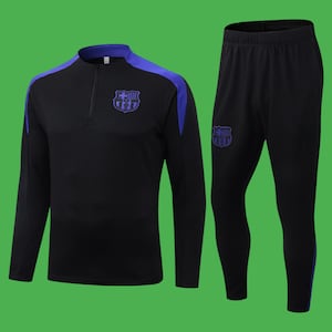 Könnte beinhalten: Schwarzer Trainingsanzug mit blauen Akzenten. Das Oberteil hat einen Viertelreißverschluss und einen blauen Kragen und Schulterpaneele. Die passende Hose hat einen blauen Streifen an der Seite. Beide Teile zeigen ein Teamlogo.
