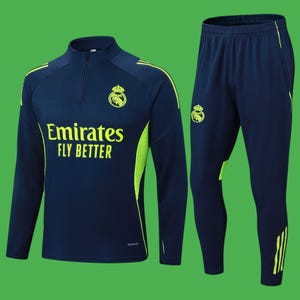 May include: Navy blue athletic tracksuit with a long-sleeve top and matching pants. The top features a half-zip, the text "Emirates FLY BETTER", and a team logo in yellow. The pants have a team logo and yellow stripes.