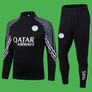 Puede incluir: Chándal negro con detalles blancos. La parte superior tiene media cremallera, el texto "QATAR AIRWAYS" y un logotipo del equipo. Los pantalones tienen un logotipo a juego y la palabra "PARIS" en blanco. Para deporte o uso casual.