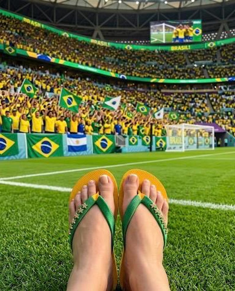 May include: Yellow and green flip-flops with star embellishments on the straps rest on a green field. In the background, a stadium is filled with fans waving Brazilian flags, creating a vibrant atmosphere.