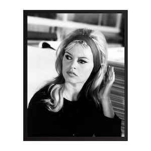 May include: Black and white framed photograph of a woman with blonde hair and a red headband. She is wearing a black top and looking off to the side. The image is a portrait.