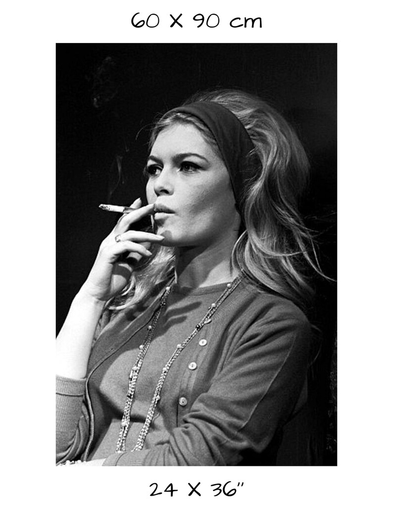 May include: Black and white print of a woman smoking a cigarette, wearing a headband and a long necklace. The print measures 24 x 36 inches. The woman is wearing a button-down cardigan. The print has a vintage aesthetic.
