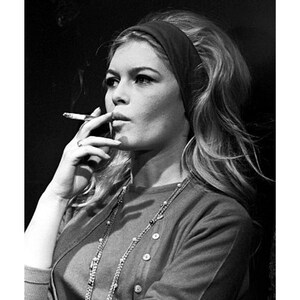 May include: Black and white portrait of a woman smoking a cigarette. She wears a headband, a cardigan, and a necklace. The print measures 11 x 14 inches, with the dimensions 27 x 35 cm printed at the top.
