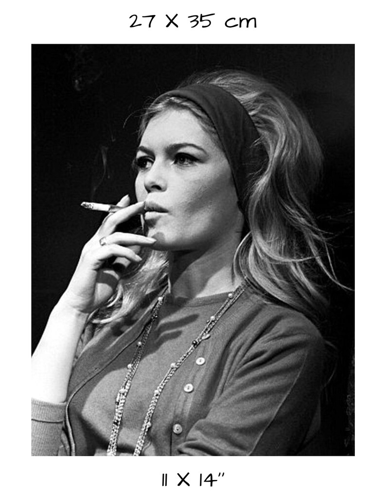 May include: Black and white portrait of a woman smoking a cigarette. She wears a headband, a cardigan, and a necklace. The print measures 11 x 14 inches, with the dimensions 27 x 35 cm printed at the top.