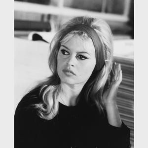 May include: Black and white photograph of a woman with blonde hair and a red headband. The image is 11 x 14 inches and the text "27 X 35 cm" is at the top. The woman is wearing a black top.
