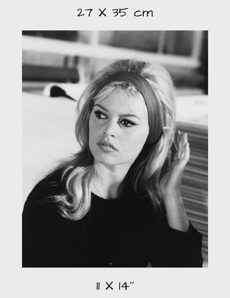 May include: Black and white photograph of a woman with blonde hair and a red headband. The image is 11 x 14 inches and the text "27 X 35 cm" is at the top. The woman is wearing a black top.