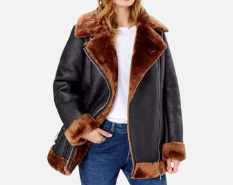 May include: Black faux leather jacket with a brown faux fur lining and trim. The jacket features a wide collar, a zipper closure, and a classic aviator style. The cuffs and hem are also trimmed with the brown faux fur.