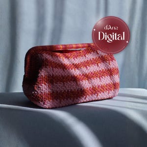 May include: A handmade, pink and orange striped crochet handbag with a matching handle. The bag has a rounded shape and a textured appearance. The image also includes a circular logo that says "dAna Digital".