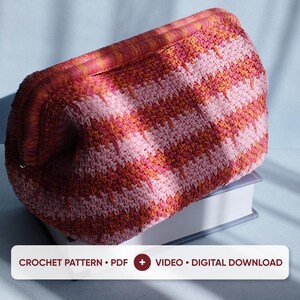 May include: A crochet pouch featuring a chevron pattern in shades of pink, orange, and red with a thick, textured frame closure. The text CROCHET PATTERN • PDF + VIDEO • DIGITAL DOWNLOAD is displayed at the bottom of the image.