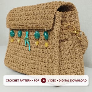 May include: A tan crocheted handbag featuring a textured weave and a flap closure. The front is adorned with a row of dangling charms, including teal and yellow beads and a central turquoise-colored branch-shaped piece. A gold metal clasp is visible.