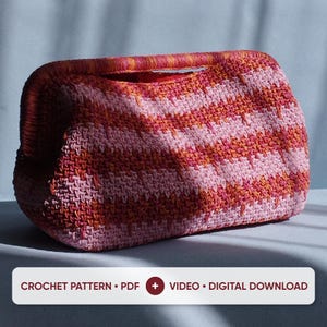May include: A crochet clutch bag featuring a horizontal striped pattern in shades of pink, orange, and red. The bag has a structured frame opening and a textured surface. A white rectangular label displays the text: CROCHET PATTERN • PDF + VIDEO • DIGITAL DOWNLOAD.