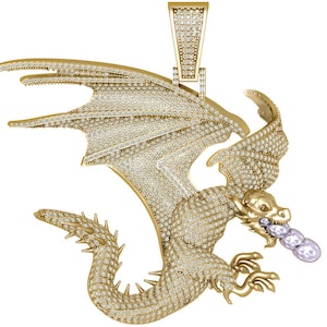 Puede incluir: Un colgante de dragón dorado, incrustado con numerosas piedras preciosas pequeñas y transparentes. El dragón tiene alas extendidas, una larga cola y exhala tres gemas redondas y claras. El colgante tiene una argolla en la parte superior para una cadena.