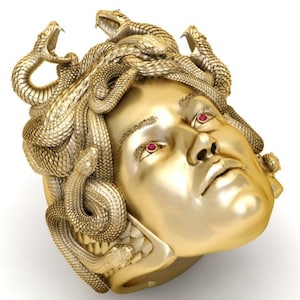 Puede incluir: Anillo dorado con diseño de cabeza de Medusa. El anillo presenta una escultura detallada de un rostro femenino con serpientes como cabello. Los ojos son rojos. Una pieza de joyería única.