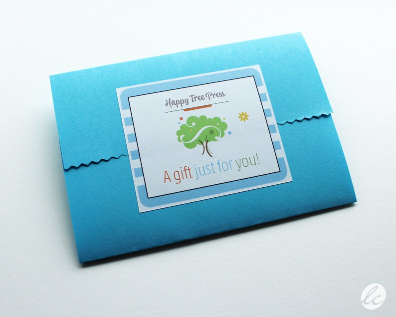 The packaging for a present which includes a blue envelope with a white label that says 'Happy Tree Press' and it's logo of a green tree with brown branches and a yellow sun. The label also says 'A gift just for you!'