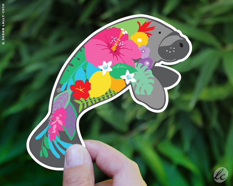 A cute, gray manatee sticker with a floral design. The manatee is outlined in white and has a colorful floral pattern of pink, yellow, red, blue, green, and white flowers and leaves.