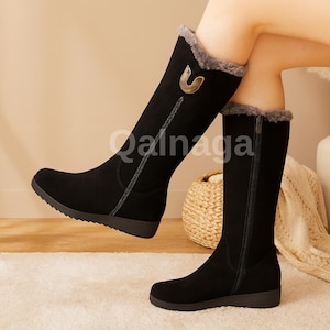 Puede incluir: Botas negras hasta la rodilla con ribete de piel sintética y cremallera lateral. Las botas tienen una hebilla decorativa dorada y un tacón bajo. Las botas son de material similar al ante.