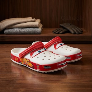 Puede incluir: Zuecos blancos y rojos con tem&aacute;tica de Cars con un dise&ntilde;o de cara de dibujos animados. Los zuecos presentan el n&uacute;mero 95 y otros gr&aacute;ficos en el lateral. Los zapatos est&aacute;n hechos de un material ligero y tienen una correa para un ajuste seguro.