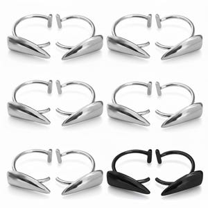 May include: A collection of six pairs of silver-toned and black metal earrings. Each earring features a curved, open hoop design with a pointed, dagger-like charm. The earrings are displayed against a white background.