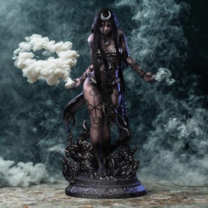 Op de afbeelding: Gedetailleerd beeld van een donkerharige figuur met een halve maan hoofdtooi, versierd met ingewikkelde lichaamskunst en sieraden. De figuur is omgeven door wervelende rook, met een wolkvorm in één hand. Het beeld staat op een gedetailleerde zwarte basis.