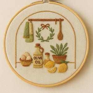 Puede incluir: Diseño bordado a mano en un aro de madera, que representa una escena de cocina. Incluye una cesta de huevos, botellas de aceite de oliva, limones y una planta. Los textos "HAND EMBROIDERY" y "PDF PATTERN GUIDE" son visibles.