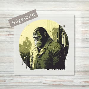 Könnte beinhalten: Illustration eines Gorillas mit grüner Jacke, vor einem gelb-schwarzen kreisförmigen Hintergrund. Das Bild hat einen Vintage-Comic-Stil mit einem Used-Look. Das Wort "Bügelbild" ist auf einem grauen Banner aufgedruckt.