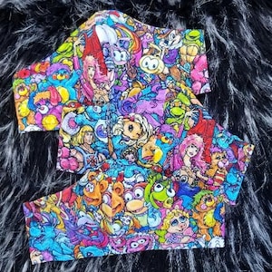 May include: A colorful fabric with a variety of cartoon characters, including a unicorn, a bear, a frog, and a pig. The fabric is perfect for making masks, bags, or other crafts.