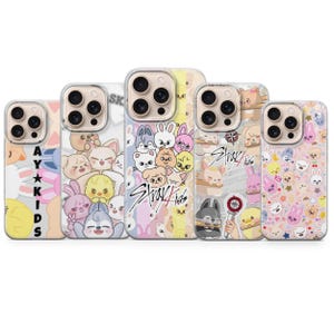 May include: Five phone cases with diverse, colourful designs. Each case displays a different pattern of cartoon characters and the text "Stray Kids". The cases have a clear border.