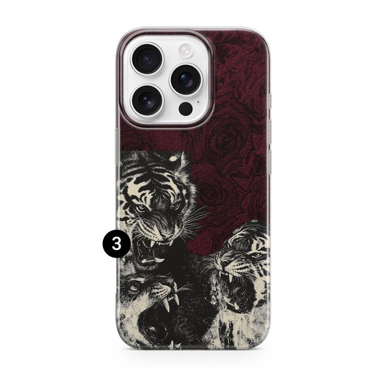 May include: A phone case featuring a detailed illustration of three roaring tigers in black and white. The background is a dark red with a subtle rose pattern. The case has a clear border and a camera cutout.