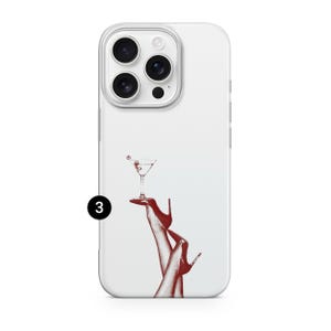 Puede incluir: Funda de tel&eacute;fono blanca con una ilustraci&oacute;n roja de una copa de c&oacute;ctel sostenida por piernas con tacones altos rojos. La funda tiene un borde transparente y un recorte para c&aacute;mara de tres lentes.