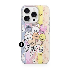 May include: A phone case featuring a colorful design with cartoon animal faces and the text "Stray Kids" in a stylized font. The case has a clear border and a multi-colored background.