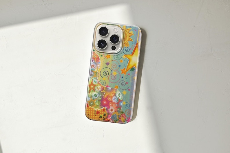 May include: A colorful phone case featuring a whimsical design with a sun, stars, and swirling patterns. The case has a clear border and a vibrant, artistic aesthetic. The design incorporates shades of blue, yellow, orange, and pink.