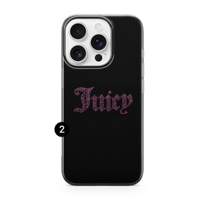 May include: Black phone case with a clear border. The case features the word "Juicy" in pink rhinestones. The phone case has a camera and flash.