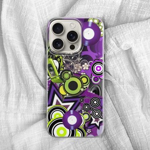 May include: A phone case with a vibrant, retro design. The case features a collage of purple, green, and black elements, including vinyl records, geometric shapes, and a flip phone. The overall theme is a bold, pop art style.