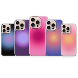 May include: Five phone cases with a gradient design. The cases are in shades of pink, purple, and blue, with a clear border around the camera. The gradient effect creates a soft, blurred look.