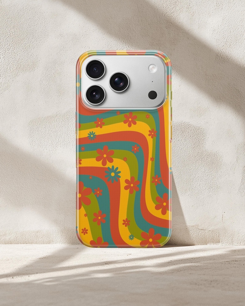 Pode incluir: Uma capa de telefone colorida com um design floral retr&ocirc;. A capa apresenta um padr&atilde;o ondulado de listras laranja, amarelas, verdes e azuis, adornado com pequenas flores vermelhas e azuis. A capa foi projetada para caber em um smartphone com um conjunto de c&acirc;meras.