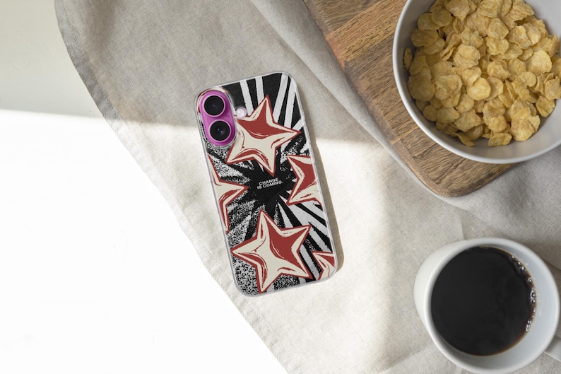 May include: A clear smartphone case featuring a graphic design of red and cream-colored stars over a black and white sunburst pattern. The text "CHANGE IS COMING" is printed in the center. The case has a purple camera lens frame and clear edges.