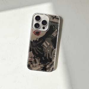 May include: Clear phone case with a printed design. The design features a black and tan graphic with a red floral accent. The case has a clear border and covers the phone's back and sides, with cutouts for the camera and buttons.
