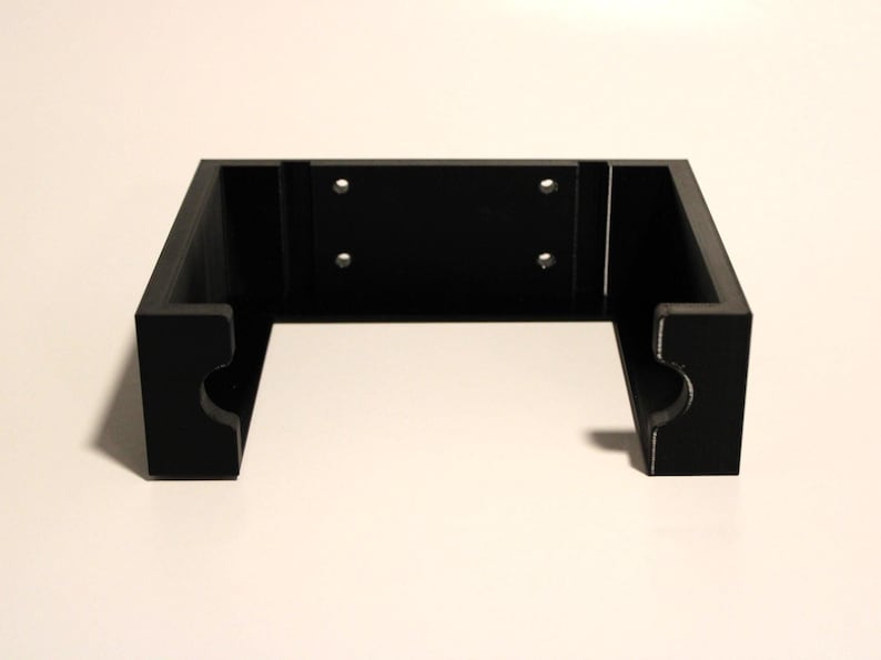 May include: A black, rectangular bracket with a recessed center section and rounded cutouts on the sides. The bracket has four pre-drilled holes for mounting. The design is simple and modern, suitable for various applications.