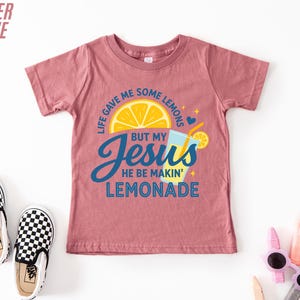 a pink t-shirt with a colorful graphic design, a pair of black and white checkered shoes, and some children's sunglasses.