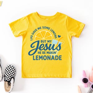 a yellow t-shirt with a humorous text and graphic design, along with a pair of black and white checkered shoes and some children's sunglasses.