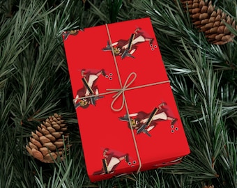 Puede incluir: Papel de regalo rojo con un patrón repetido de un personaje con una motosierra. El regalo envuelto está atado con hilo y colocado sobre un fondo de agujas de pino y piñas, creando un tema festivo de vacaciones.