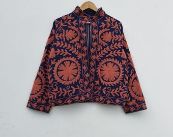 May include: A navy blue jacket with intricate rust-colored floral embroidery. The jacket features a high collar and a button closure. The embroidery creates a striking contrast against the dark background, showcasing a detailed pattern of flowers and leaves.