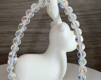 May include: A circular bracelet composed of translucent, iridescent beads with a subtle rainbow sheen. The beads are strung together in a continuous loop, and the text 5.2mm is printed in the bottom right corner, indicating the bead size.