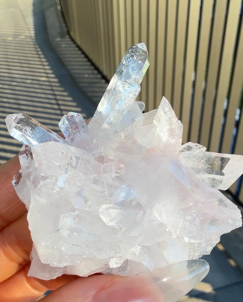 May include: A cluster of clear, translucent quartz crystals with sharp, pointed terminations and multifaceted surfaces. The mineral formation features a bright, icy white appearance with varying degrees of transparency and natural geometric facets.