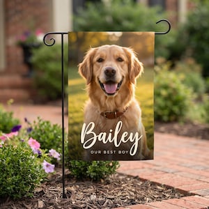 May include: A rectangular garden flag featuring a photographic portrait of a golden retriever wearing a brown collar. The dog has its mouth open with its tongue visible. The text "Bailey" is printed in white script, with "OUR BEST BOY" below.